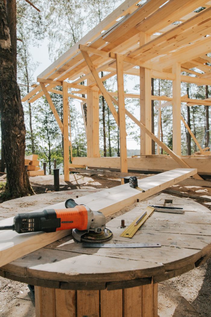 Home A scenic view of woodworking tools and wooden frame at a forest construction site.