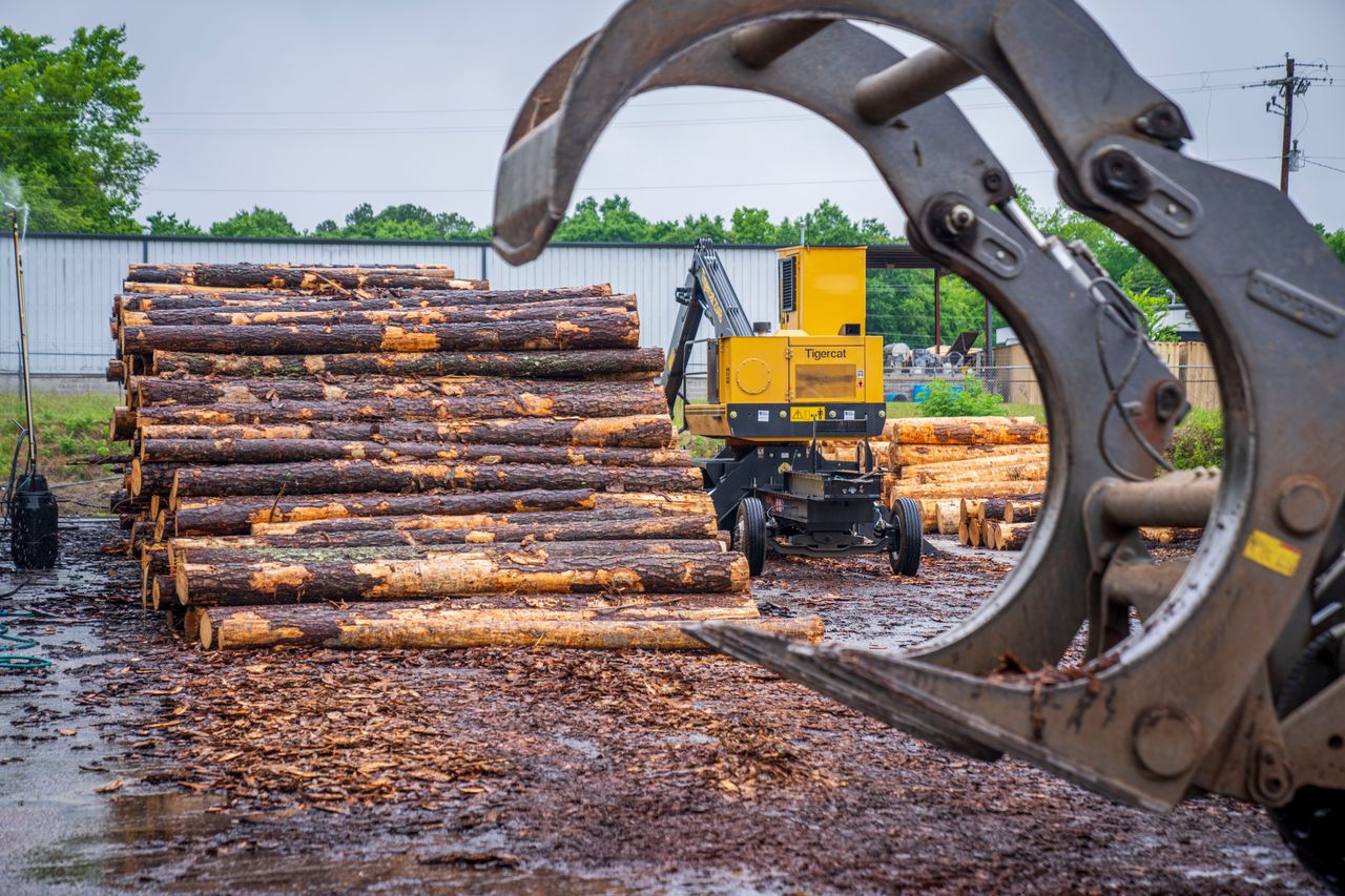 The Art of Drawing Readers In: Your attractive post title goes here Heavy machinery stacking timber logs at an industrial site amid a natural backdrop.